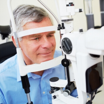 a man sits in a special chair that holds his head still for an eye exam