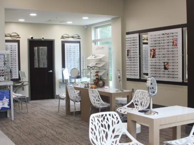 View of the FIrst Look Opticians inner room, well lit by windows, glasses selection all along the walls, small desks for meeting with the opticians.