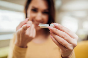 a woman looks at a contact lens