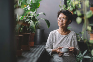 an elder woman wearing glasses and drinking tea