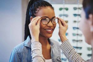 Attractive young African woman selecting glasses with the help of an optometrist in a store trying on different frames